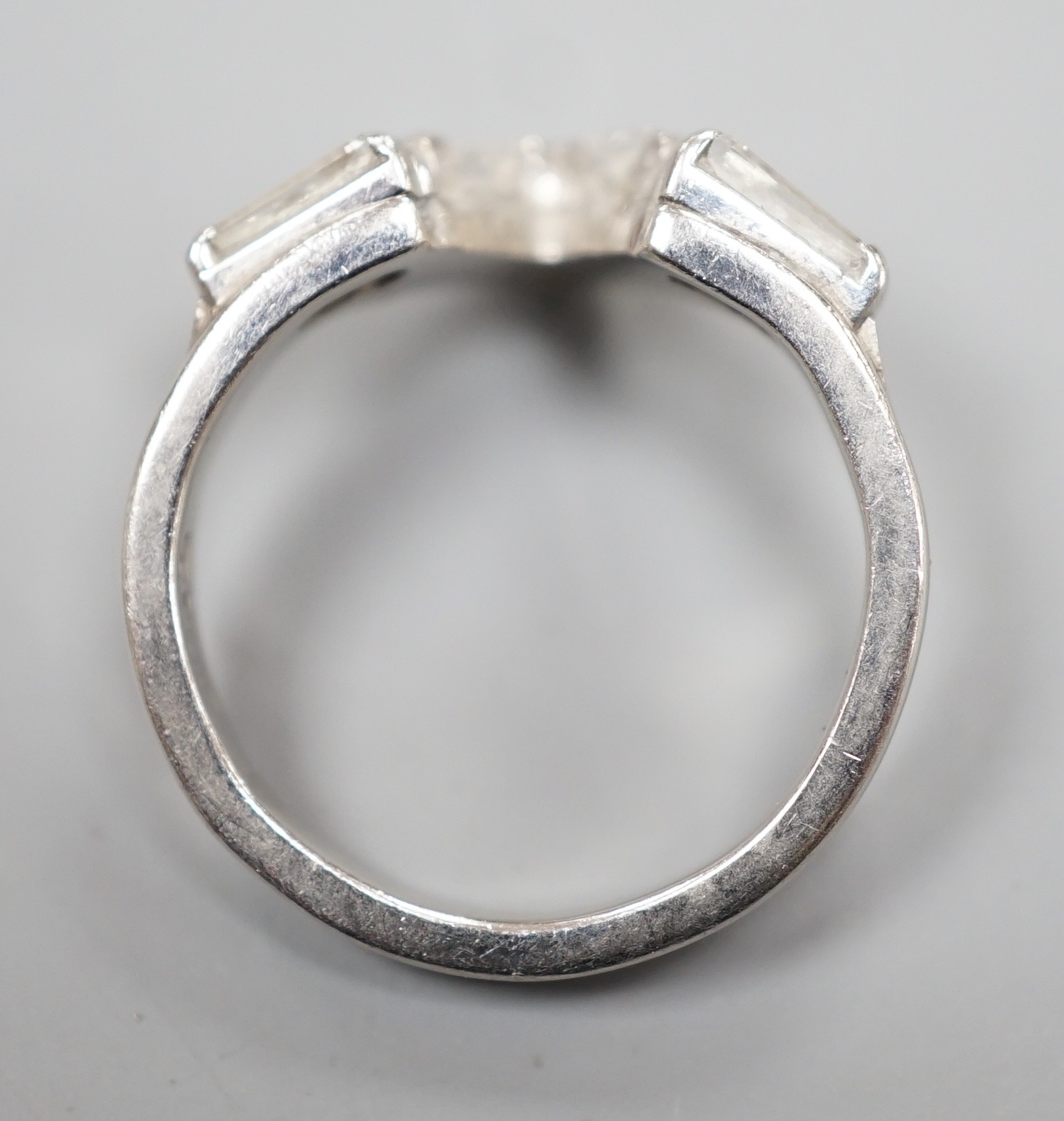 A modern white metal (stamped plat), two stone trapeze cut and three stone princess cut diamond set 'chevron' ring, size I, gross weight 5.3 grams.